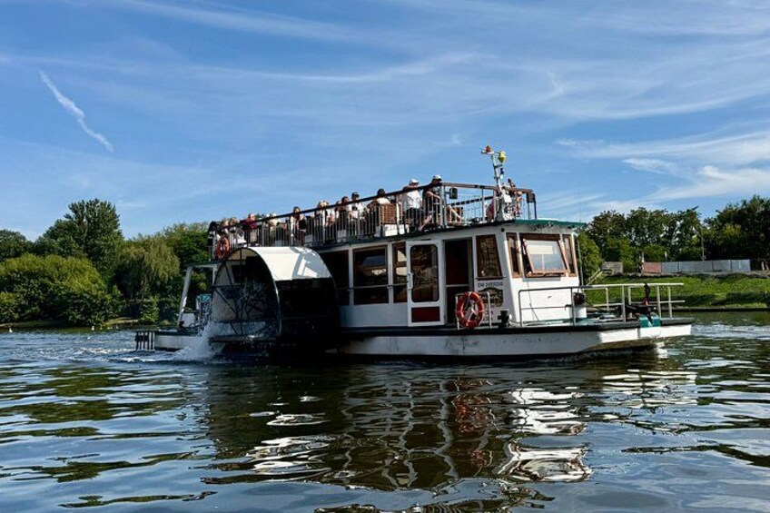A riverboat with a covered upper deck, passengers, and a life preserver on the side. 4