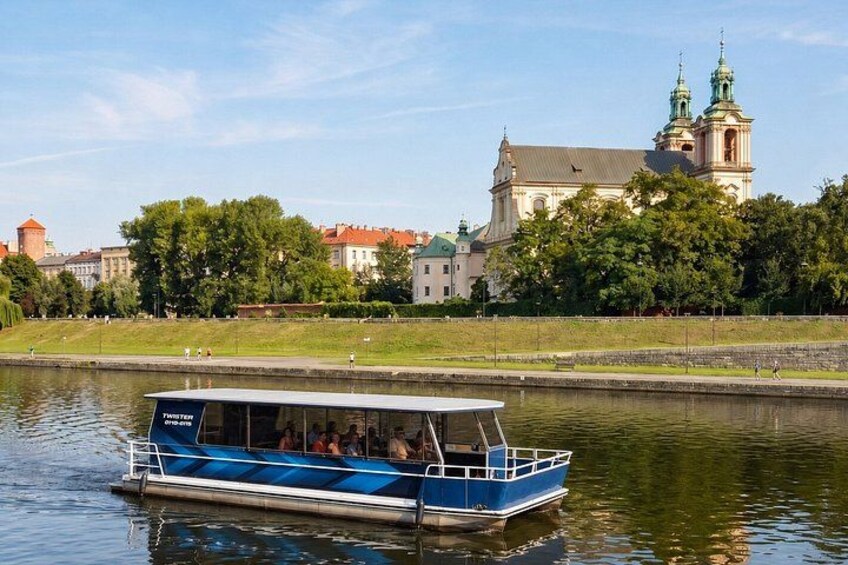 A blue boat with passengers on a river, a church with a green spire, and trees along the riverbank. 5
