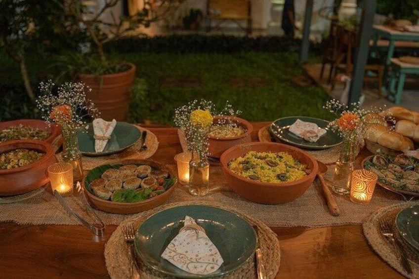 An outdoor dining setup with terracotta bowls, candles, and flowers. 3