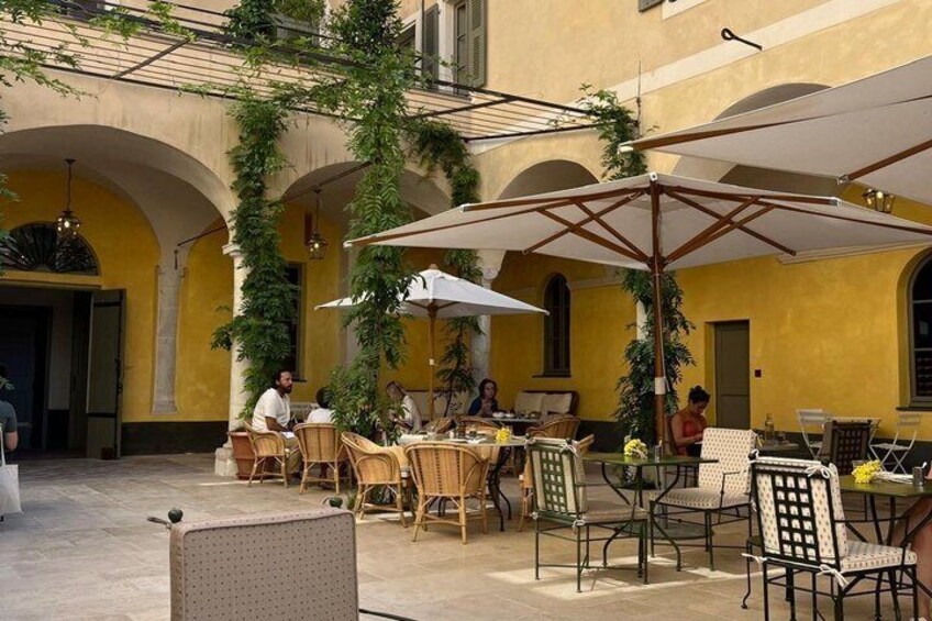 An outdoor cafe with yellow walls, wicker chairs, and umbrellas. 4