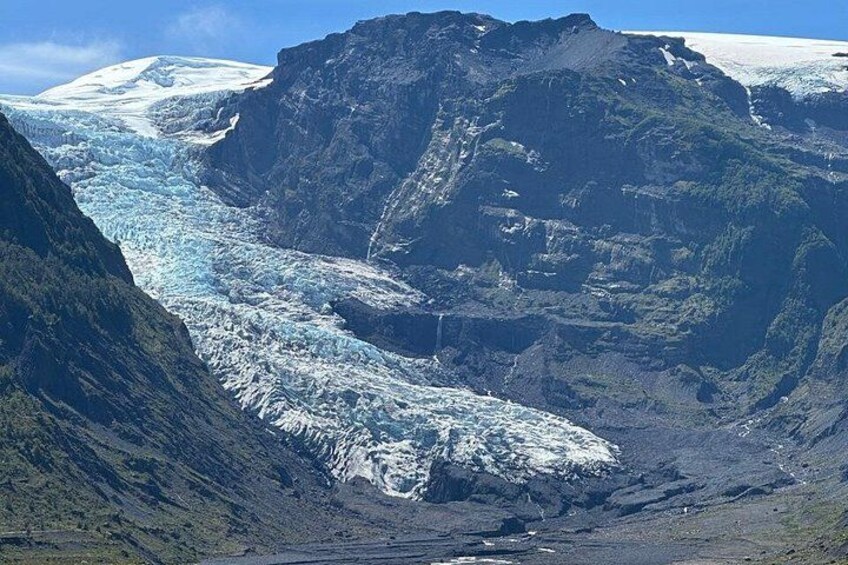 A glacier with a steep valley, snow-capped mountains, and rugged terrain. 4