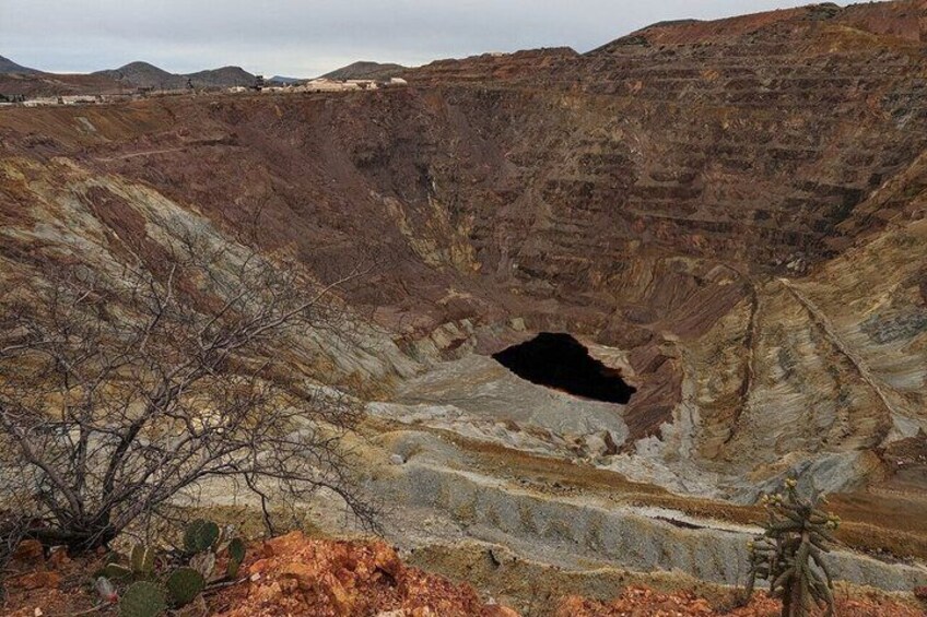 A barren landscape with a large crater-like depression surrounded by rugged terrain. 2