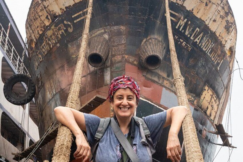 A person standing in front of a large, rusted ship with ropes and a ladder. 2