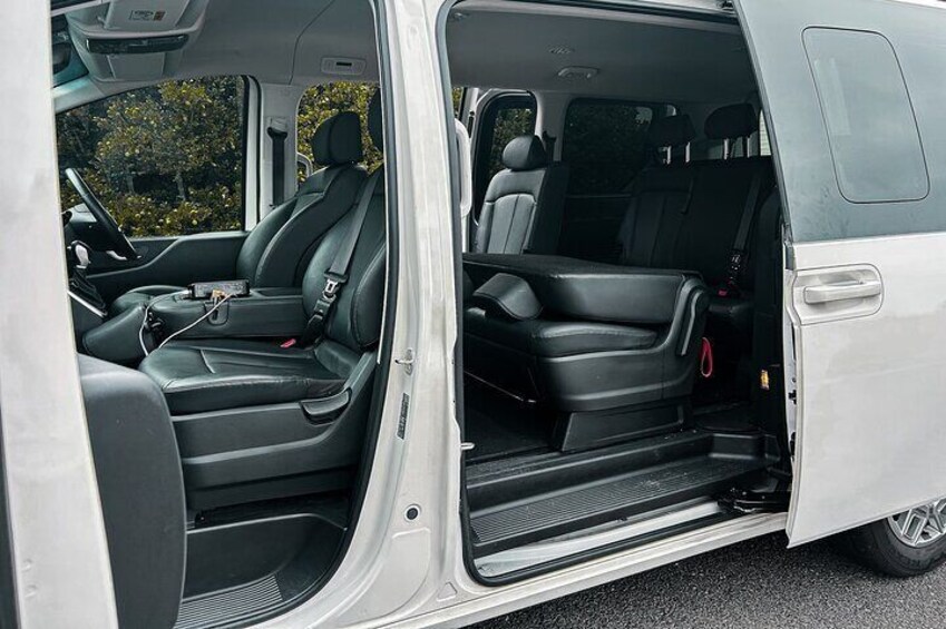 A white van with black interior, open door, and visible steps leading to the rear. 4