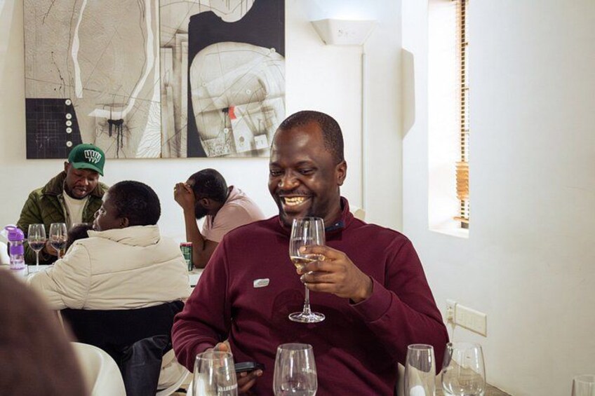 A person holding a wine glass at a table in a restaurant with other diners. 2