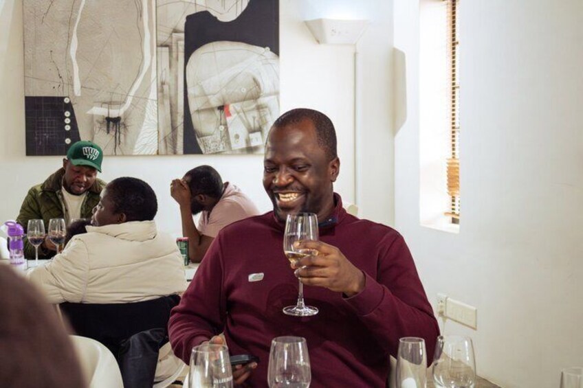 A person holding a wine glass, seated at a table with other diners. 2