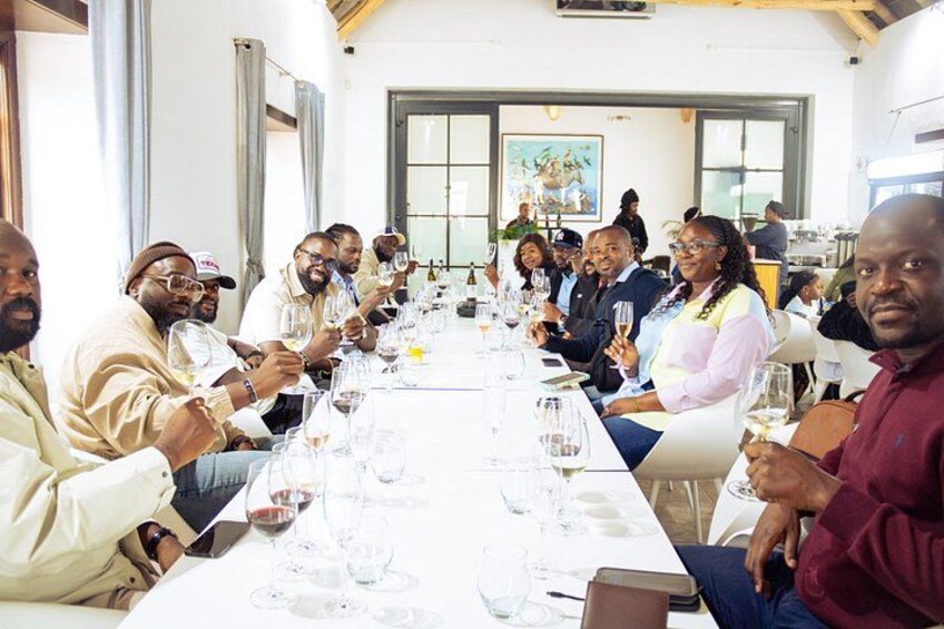 A group of people seated at a long table with wine glasses, engaged in a social gathering. 3