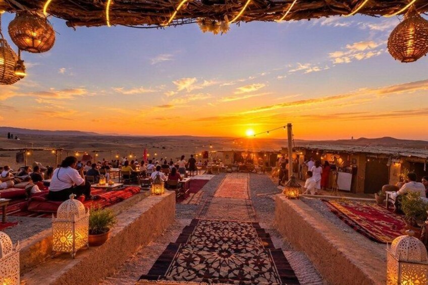 A sunset at a rooftop dining area with people seated and tables set up. 1