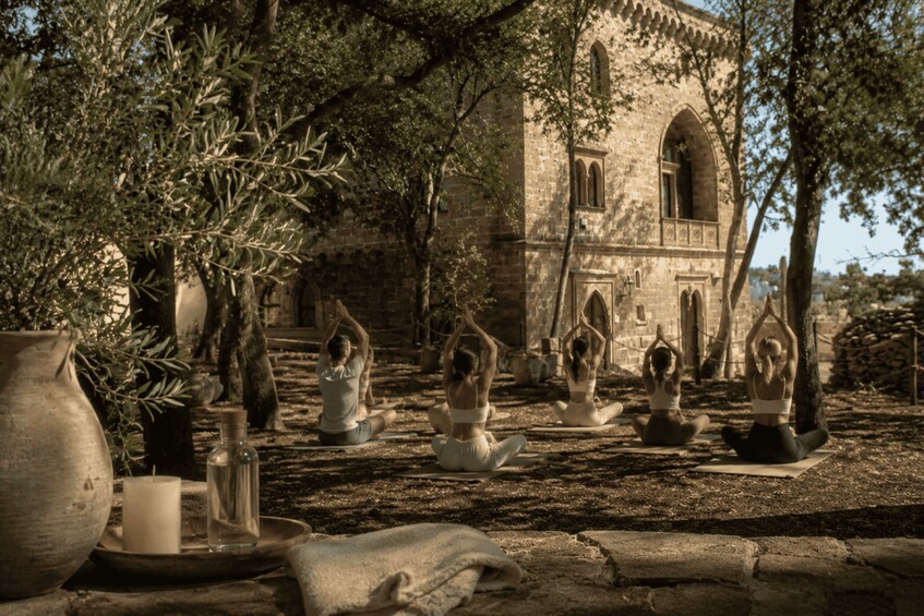 A group of people practicing yoga outdoors with a historic building in the background. 3