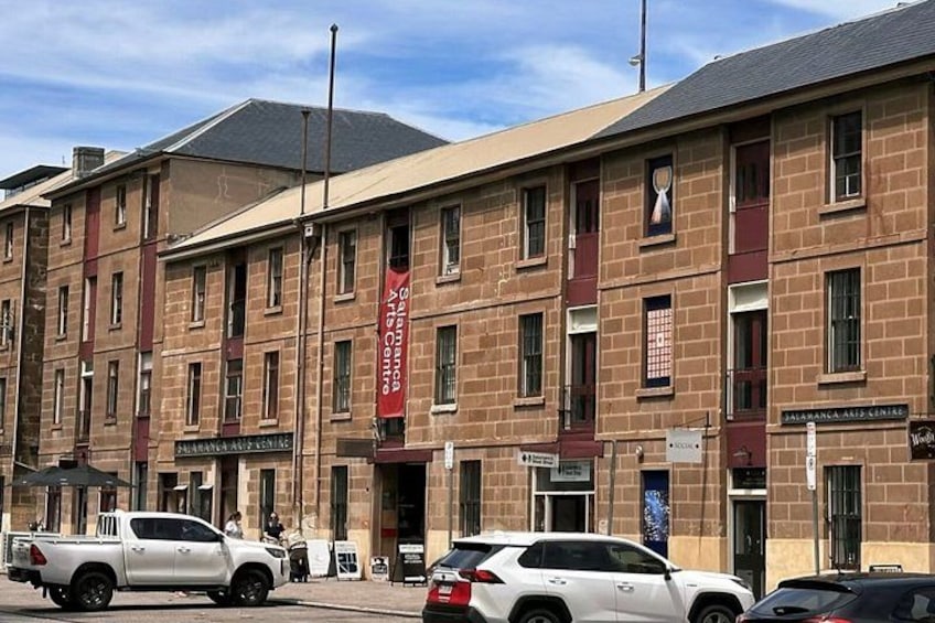 A multi-story building with a red banner, parked cars, and a clear sky. 5