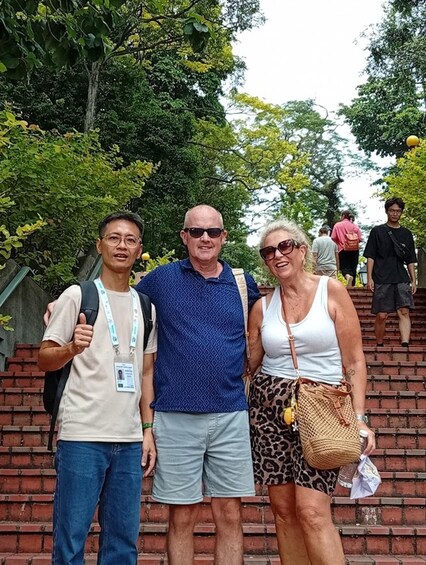 Three people standing on a brick staircase with greenery in the background. 2