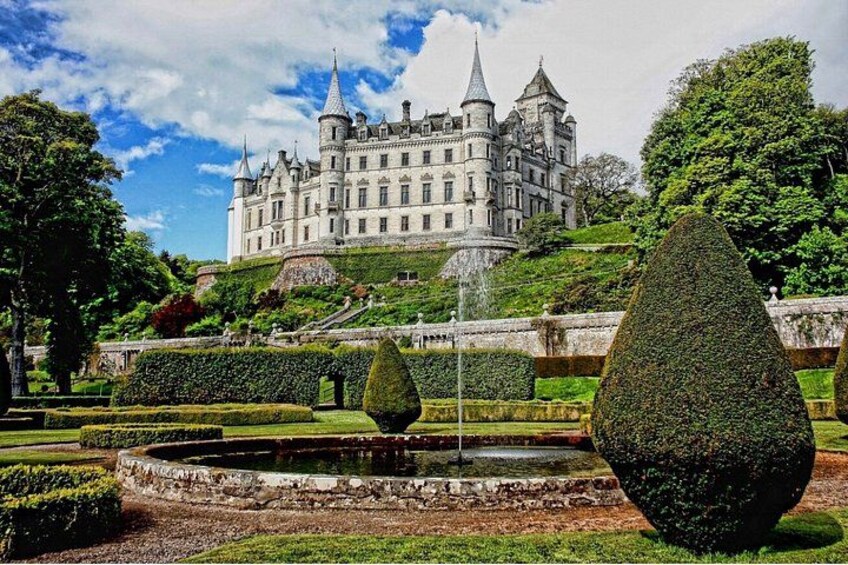 A castle with a large garden, a fountain, and a well-maintained lawn. 4