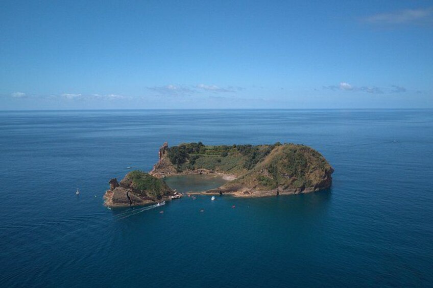 A coastal landscape with a prominent rocky island surrounded by calm blue waters. 1