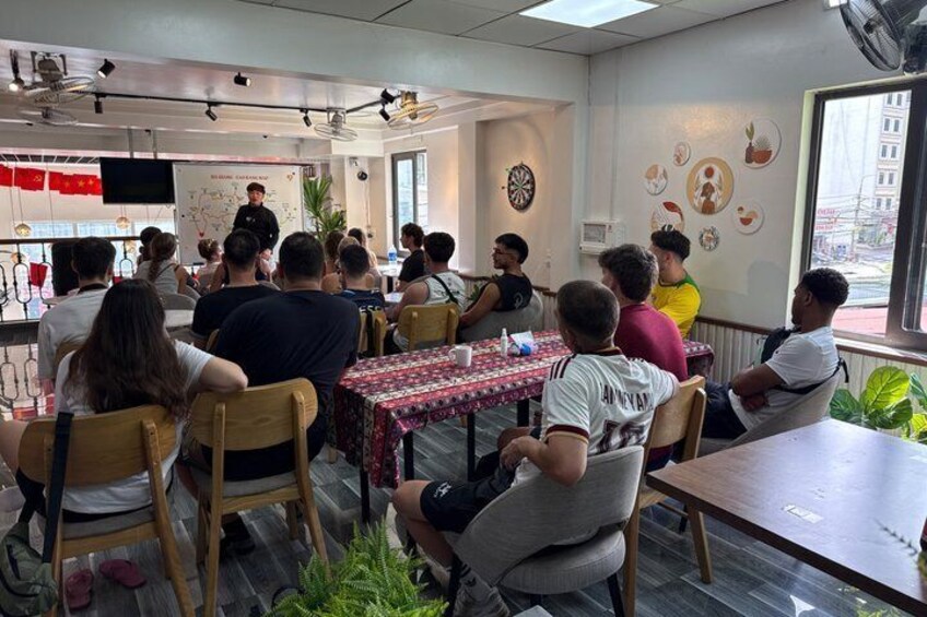A group of people seated at tables in a cafe with a presentation in the background. 4