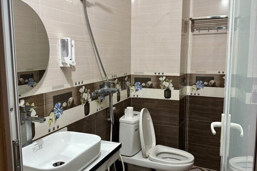 A bathroom with a white sink, toilet, and shower. 2