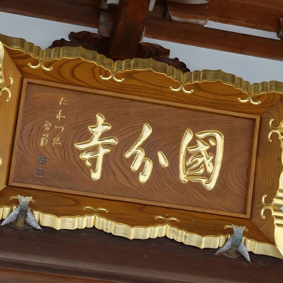A wooden sign with gold lettering and decorative elements. 5
