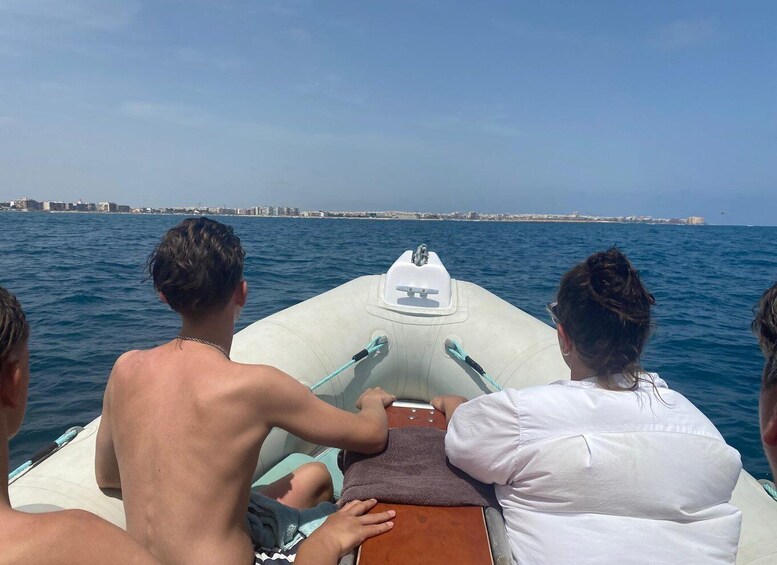 Three people on a small boat with a cityscape in the background. 2