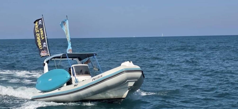 A small motorboat with a blue and white color scheme, a flag, and a registration number on the back. 4