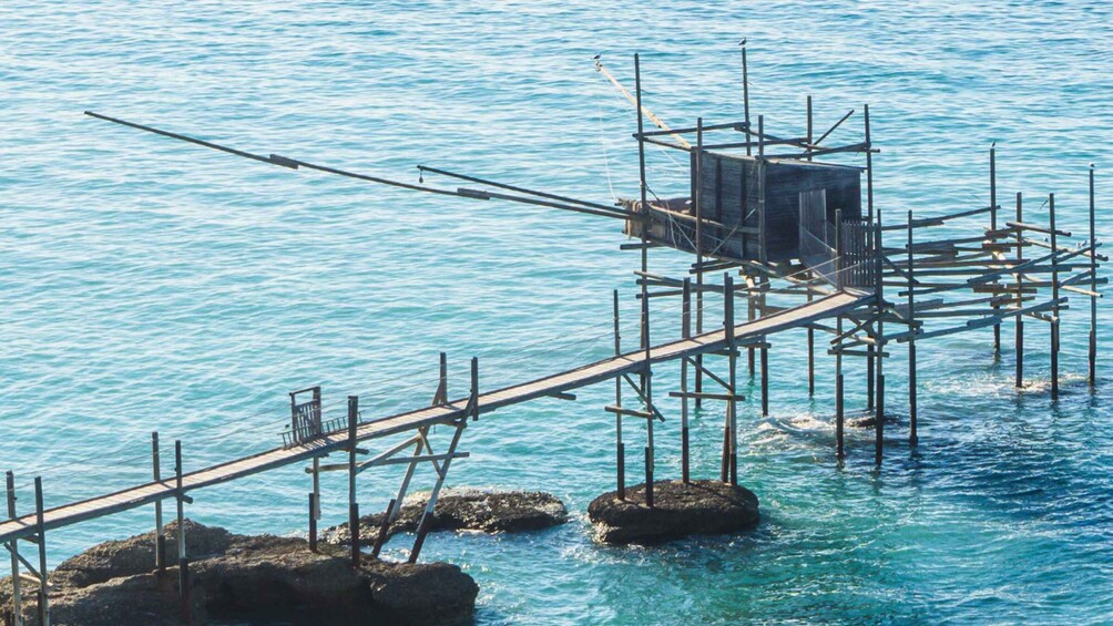 A wooden pier extending into a body of water, supported by rocks and wooden posts. 2