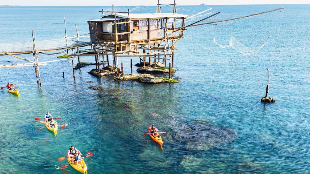 A wooden structure on stilts in the water with people kayaking around it. 5