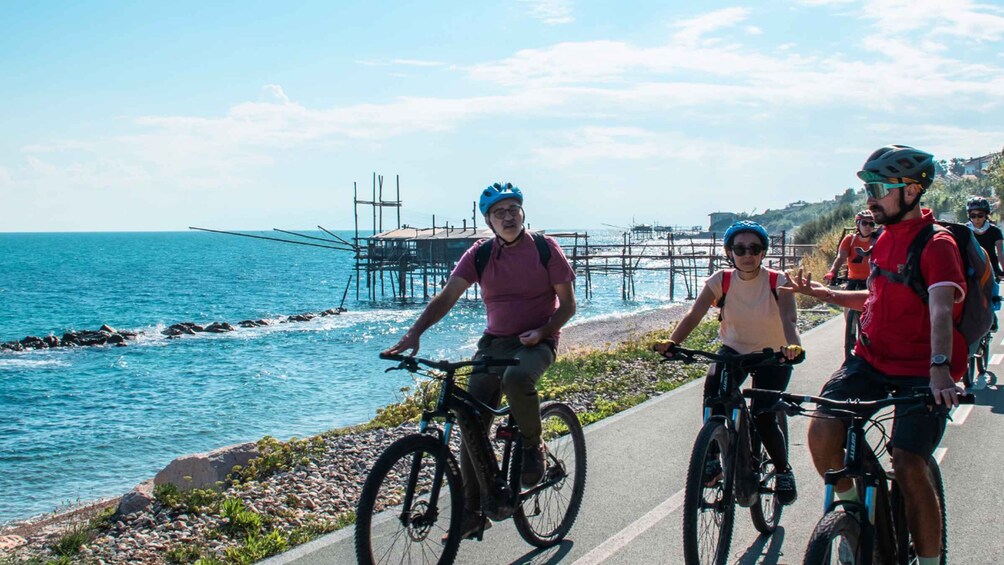 Cyclists on a coastal road with a pier in the background. 1