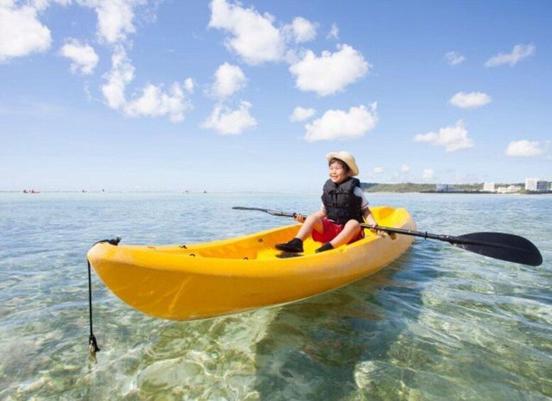 A person in a yellow kayak on clear water with a city skyline in the background. 5