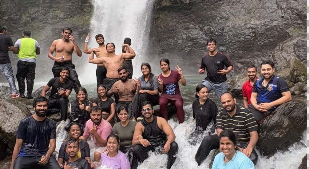 A group of people gathered around a waterfall with water flowing over rocks. 3