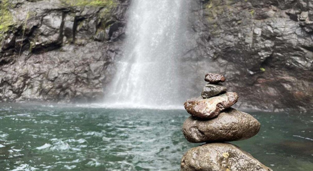 A waterfall, clear water, and a stack of rocks. 1