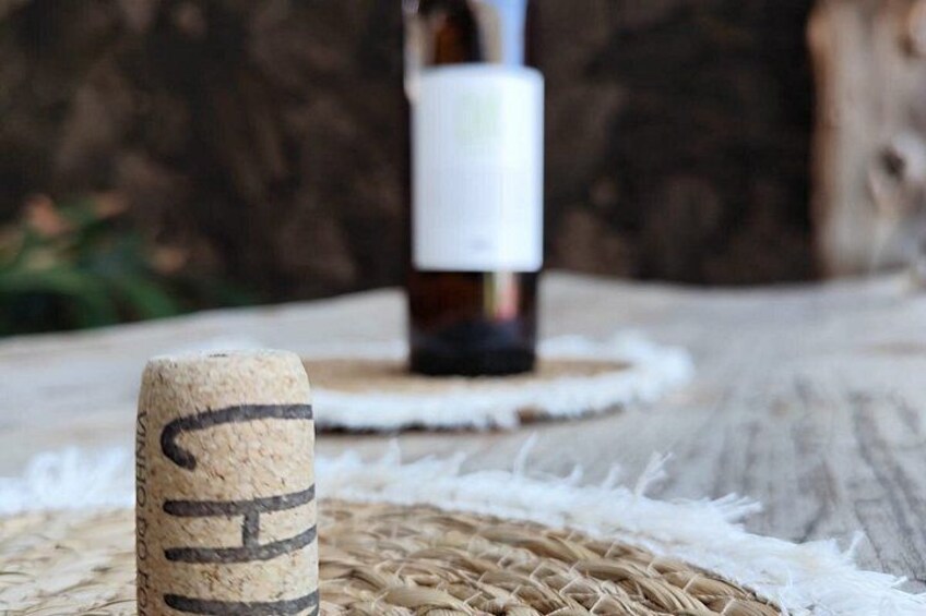 A cork with 'TH' carved on it, a bottle, and a rustic wooden surface. 4