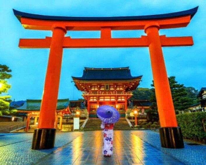 A traditional Japanese torii gate with a person walking towards a building with a tiled roof. 5