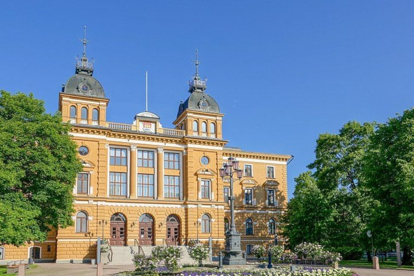 Ein großes, verziertes Gebäude mit zwei Kuppeln und einer Statue davor. 1