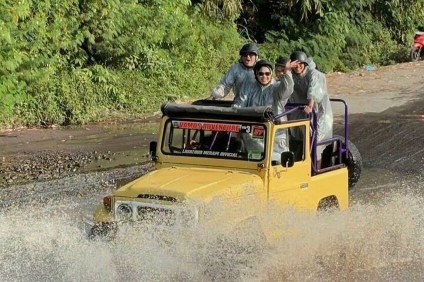 A yellow off-road vehicle with people driving through a shallow water body. 5