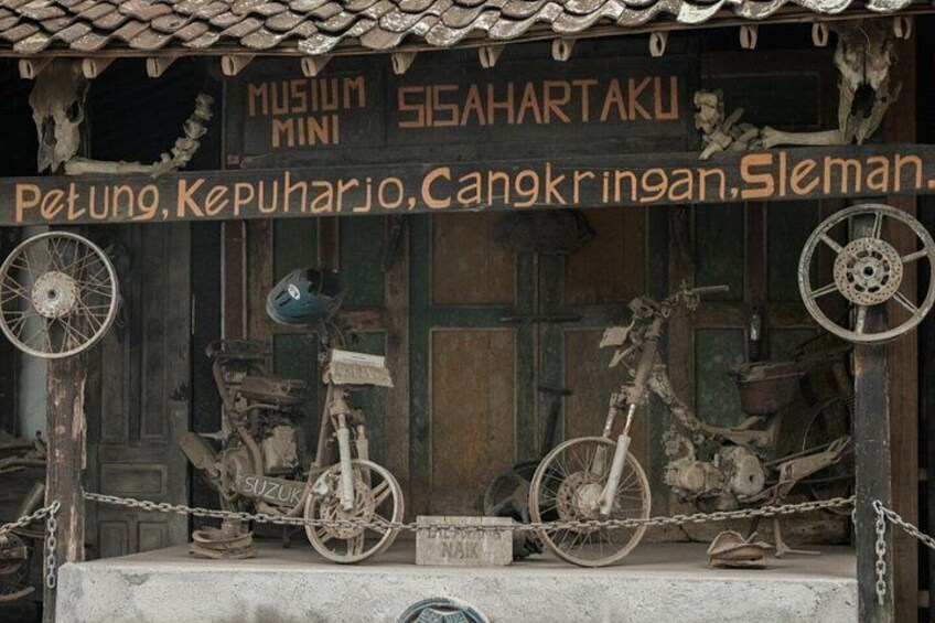 A rustic building with a sign reading 'MUSIUM MINI SISAHARTAKU' and a list of items including 'Petung, Kepuharjo, Cangkringan, Sleman.' 4