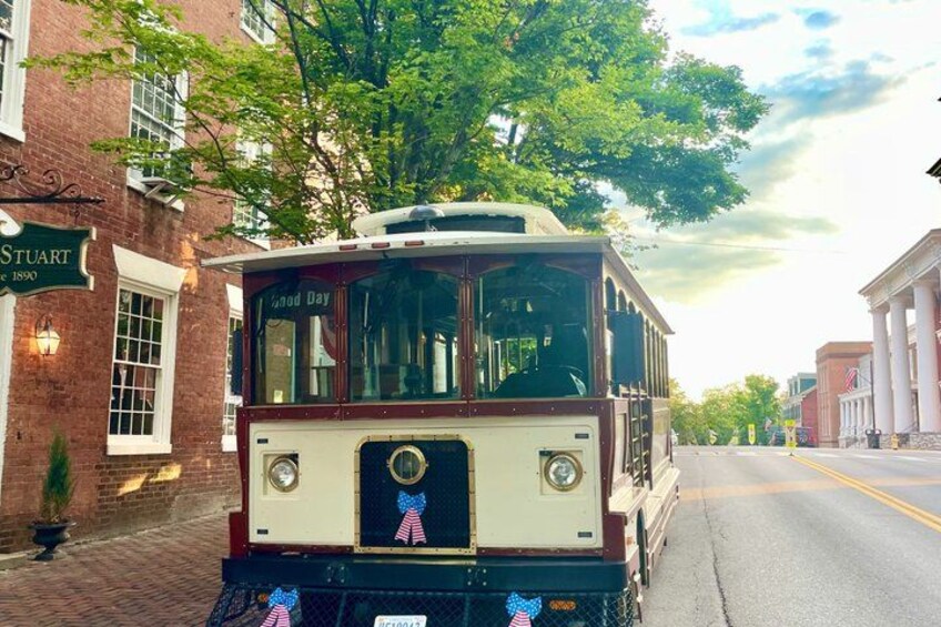 A vintage trolley parked on a street with a brick building and a sign that reads 'STUART'. 4