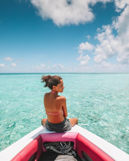 A person sitting on a boat in turquoise waters under a clear sky. 2