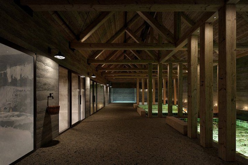 A long corridor with wooden beams, a concrete floor, and a large window on the left. 4