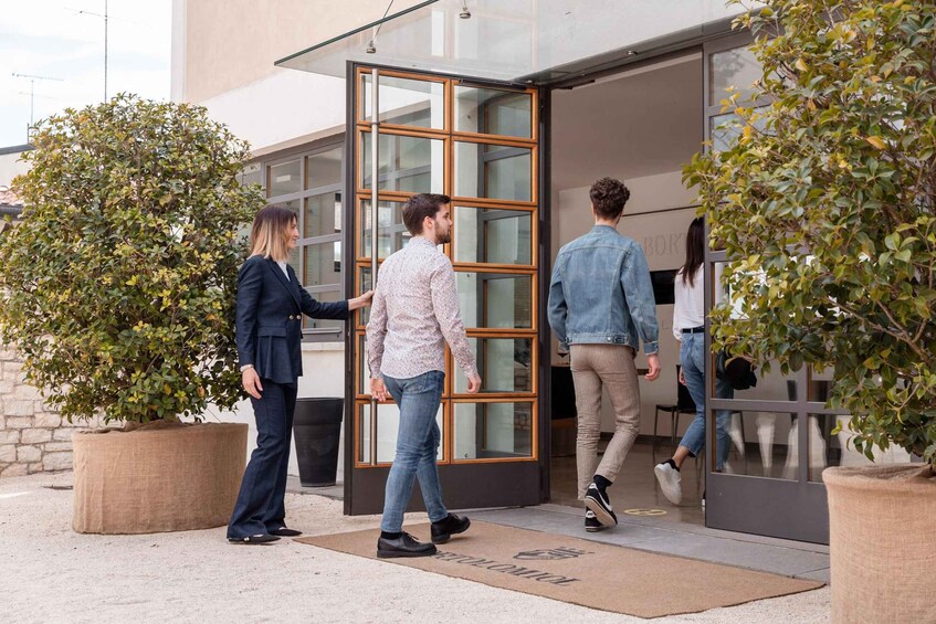 People exiting a building with glass doors and potted plants. 5