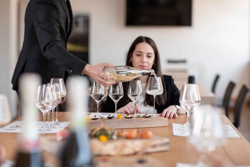 A person pouring a drink into glasses at a table with a menu. 3
