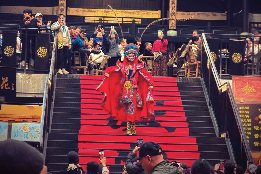A performer in traditional costume descending a red staircase. 3