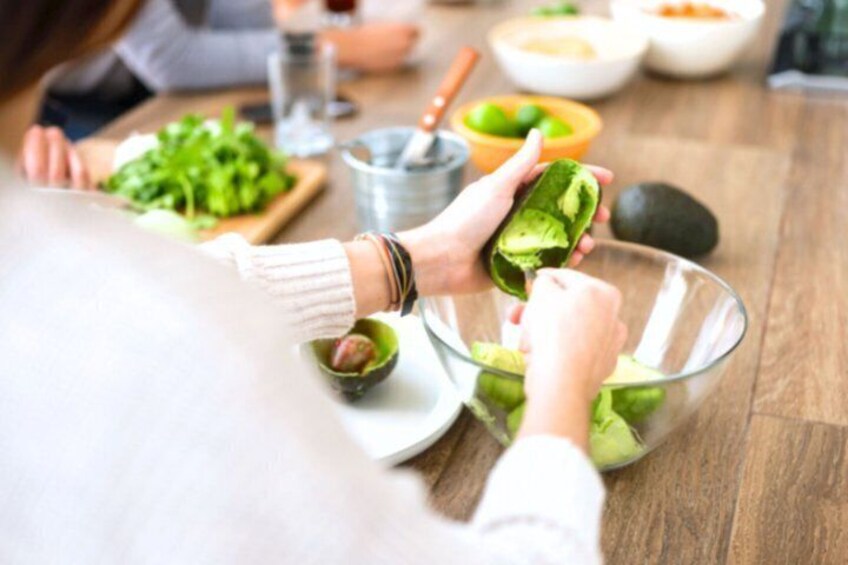 A person preparing food, with a bowl, avocado, and a cutting board visible. 1