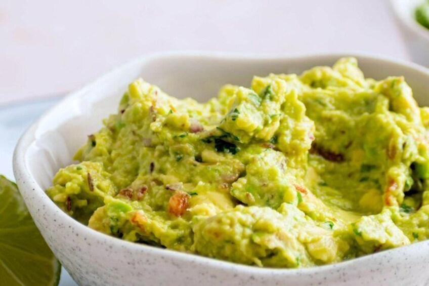 A bowl of guacamole with visible chunks of avocado and herbs. 5