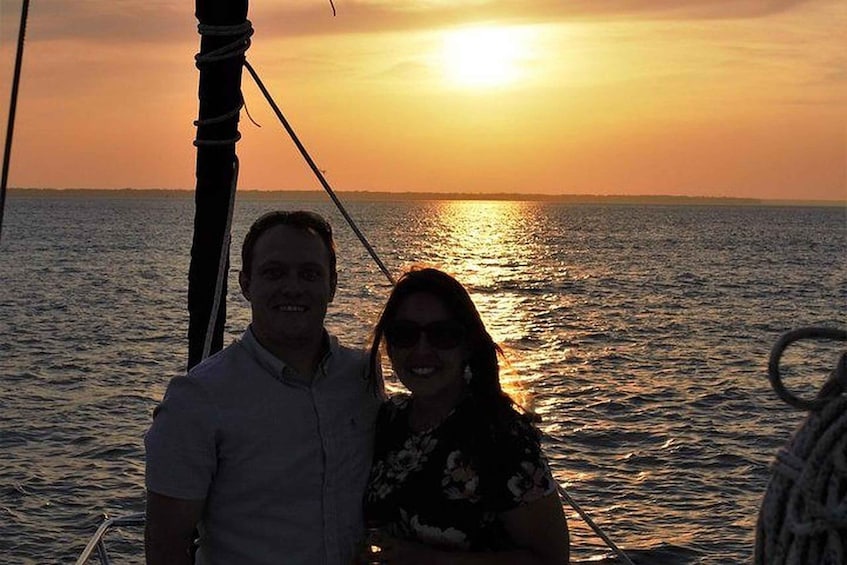 A couple on a boat with the sun setting over the water. 3