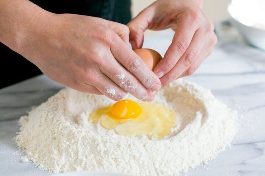 Hands mixing flour with an egg in a bowl. 3