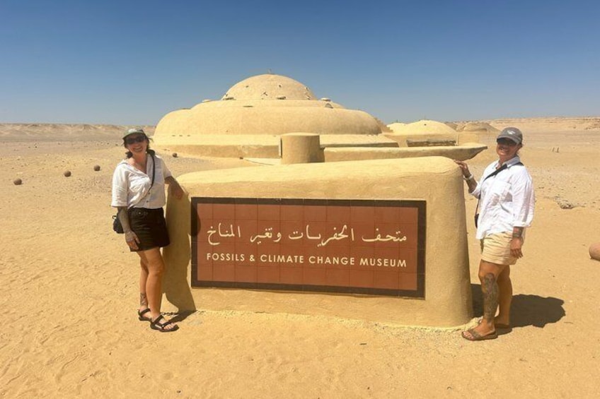 Two people standing in front of a sign for the Fossils & Climate Change Museum. 5