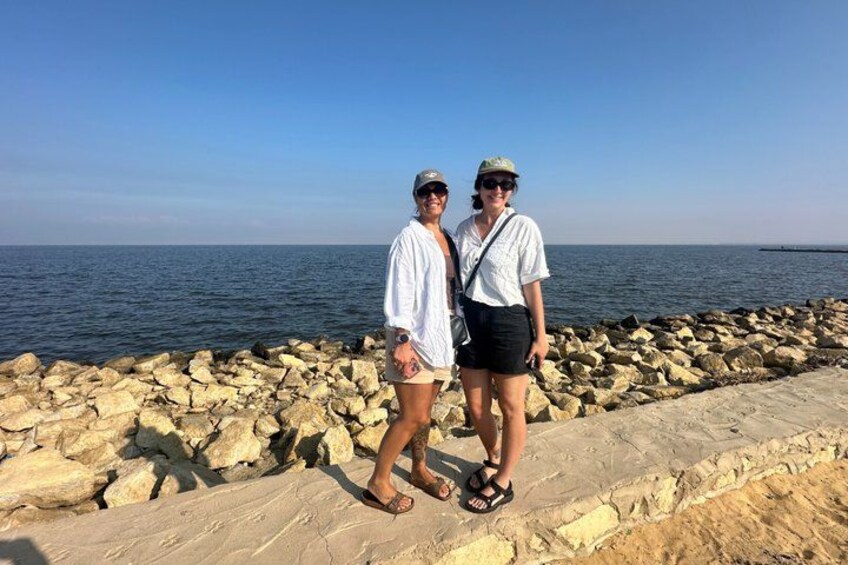 Two people standing on a rocky seaside path with the ocean in the background. 3