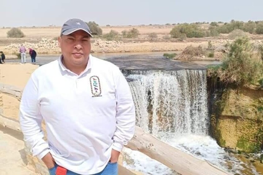 A person standing in front of a waterfall with a river flowing through it. 2