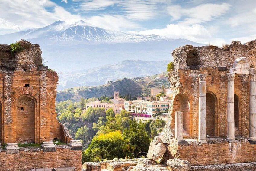 Ancient ruins with columns, a mountain in the background, and a town with buildings. 2