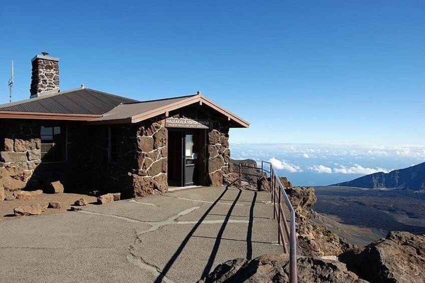A stone building with a sign, a paved path, and a view of a mountain range. 1