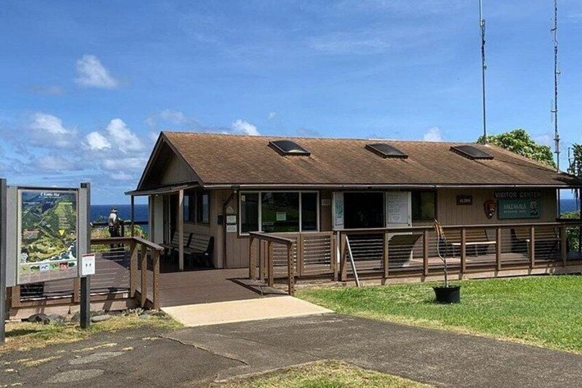A visitor center with a wooden structure, a paved entrance, and a grassy area. 4