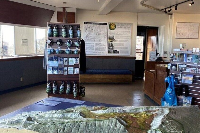 A room with a display of water bottles, a map on the wall, and a large map on the floor. 2